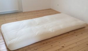 Auf einem Futon schlafen: Foto eines weissen Futons auf einem Holzdielenboden