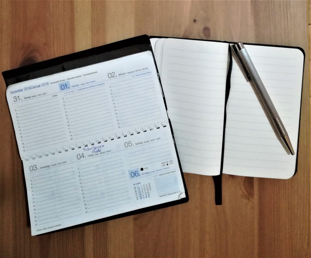 Kalender, kleines Notizbuch und Kugelschreiber