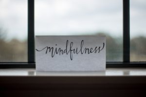 handgeschriebenes Papier mit Aufschrift "Mindfulness" an einem Fenster stehend.
