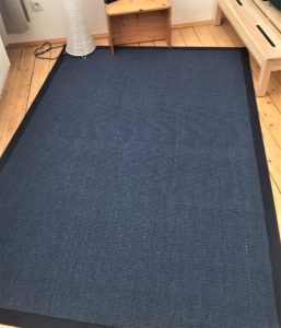 blauer Sisalteppich auf Holzdielenboden