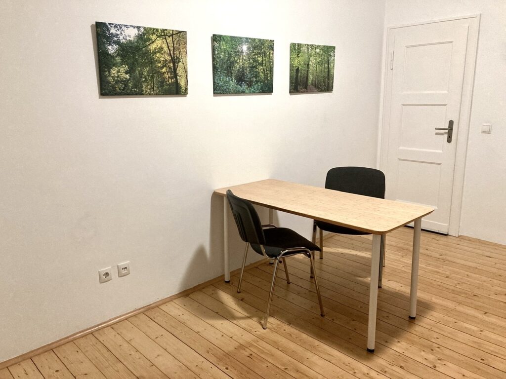 Tisch mit 2 Stühlen, an der Wand 3 Naturbilder