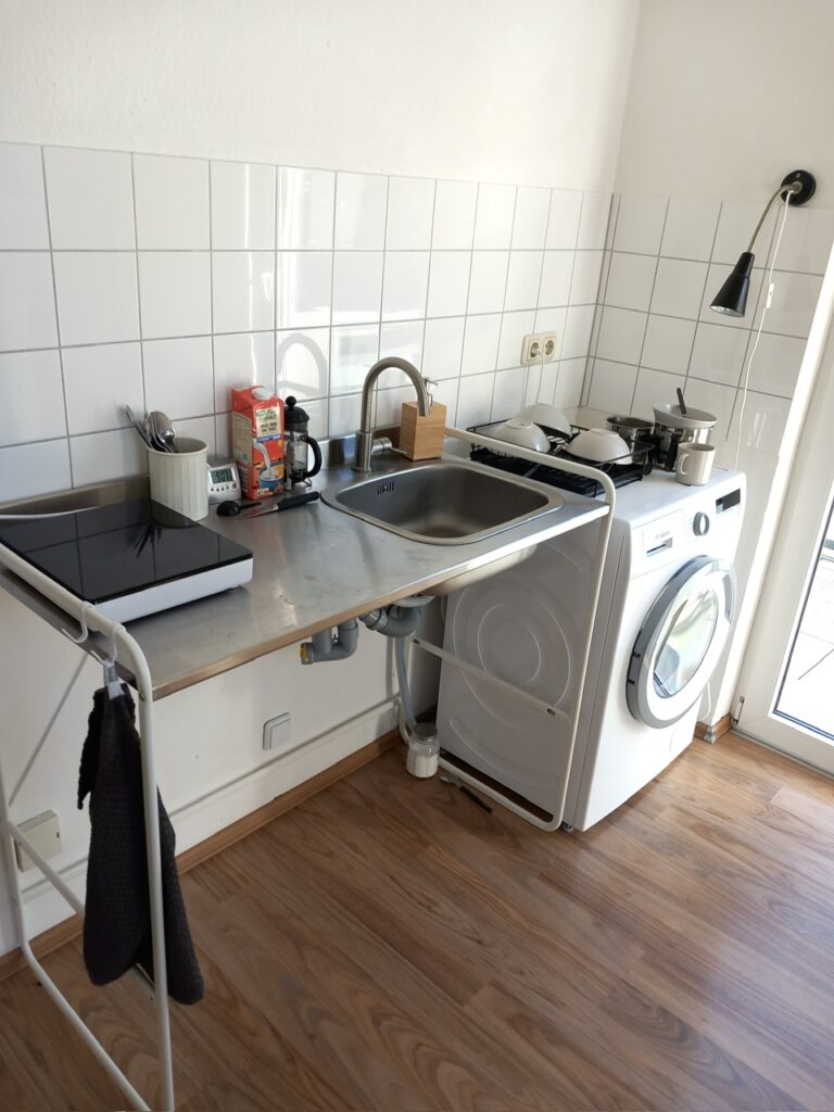 Spüle mit mobiler Kochplatte, rechts daneben eine Waschmaschine